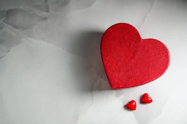 Sevgililer Günü geçmişi. Kırmızı kalp hediye kutusu ve parlak mermer zemin üzerinde iki küçük kalp, kopyalama alanı.