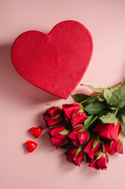 Sevgililer Günü geçmişi. Kırmızı güller çiçekler ve parlak arka planda kalp hediye kutusu. Kutlama kartı, düz yatış.