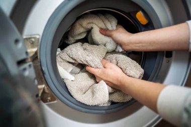 Çamaşır makinesi evde. Akıllı aletler. Çamaşır makinesini havlularla dolduran kadın. Günlük ev işleri. Çamaşır yıkama..