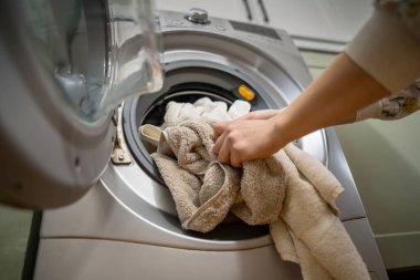 Çamaşır makinesi evde. Akıllı aletler. Çamaşır makinesini havlularla dolduran kadın. Günlük ev işleri. Çamaşır yıkama..