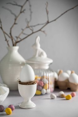 Paskalya arkaplanı, bahar süslemeleri olan masa: yumurta, şeker, vazodaki dallar ve yumurta şekeri
