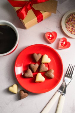 Sevgililer Günü çikolataları kırmızı tabakta bir fincan kahve ve mumla servis ediliyor. düz yat