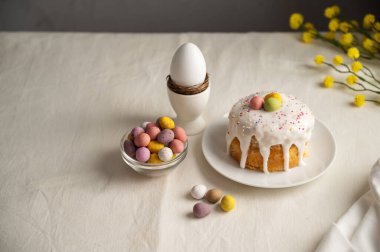 Paskalya bayramı pastası, kremalı, şekerli ve yumurtalı. Beyaz yumurta ve bahar, sarı çiçek dalları.