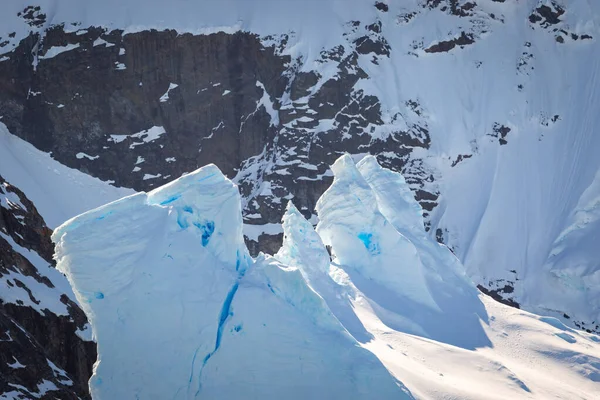 Antarktika 'nın arka planında taş bir dağ olan bir buzdağının mavi parçası.
