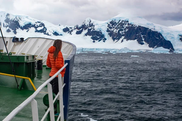 Bir kız Antarktika 'da bir yolcu gemisinin pruvasında duruyor ve manzaranın tadını çıkarıyor..