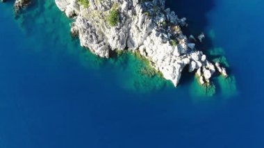 Temiz mavi suyla çevrili küçük kayalık bir adanın üzerinden uç. Hava aracı atışı. 4K