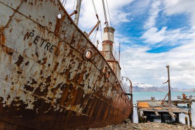 Grytviken 'de terk edilmiş bir balina avlama üssünde iskelesi olan eski paslı bir gemi. Güney Georgia.