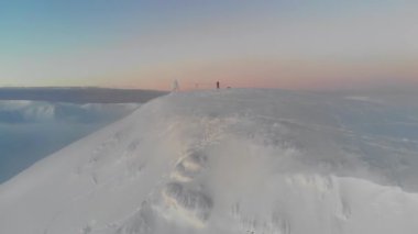 Bir adam karlı bir dağın tepesinde duruyor. İnsansız hava aracının görüntüsü. Hava görünümü.