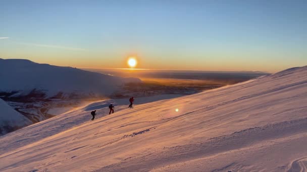 Folk åker skidor i bergen i blåsigt väder vid solnedgången. — Stockvideo