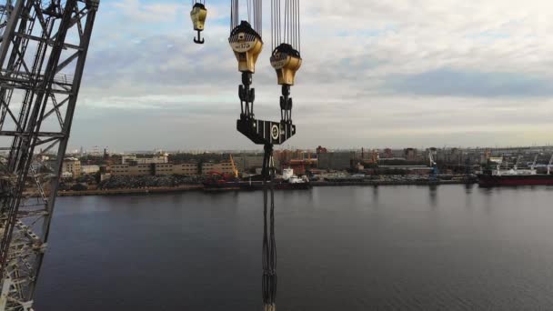 Grande guindaste e ganchos com um porto de carga no fundo. Ganchos de guindaste de várias toneladas de perto. Um guindaste de várias toneladas para navios na área de reparo portuário. Atirador de drones. — Vídeo de Stock