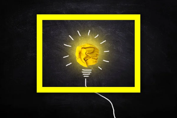 Business Idea Concept : Yellow crumpled paper ball light bulb lighting grow around on chalkboard in yellow frame.