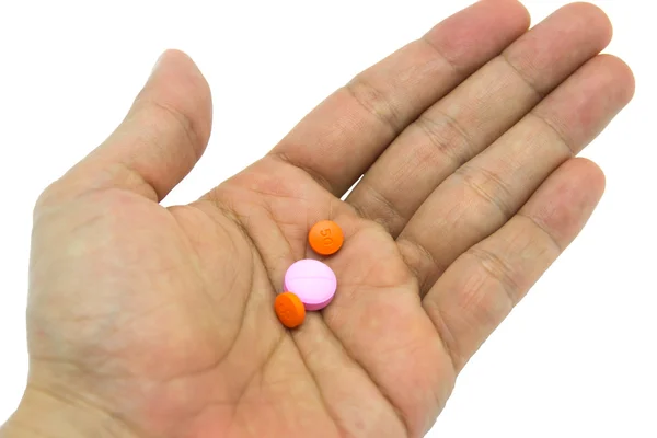 Mão segurando pílulas no fundo branco — Fotografia de Stock