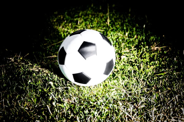Soccer football ball on grass field with light effect — Stock Photo, Image