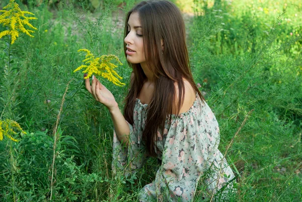 Милая девушка вдыхает аромат диких цветов. — стоковое фото