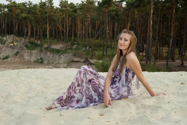 Mulher atraente em areia perto de madeiras de pinheiro — Fotografia de Stock