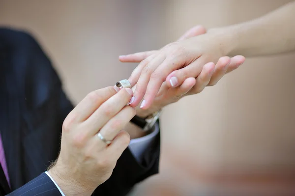 Noivos mão colocando um anel de casamento no dedo noivas — Fotografia de Stock