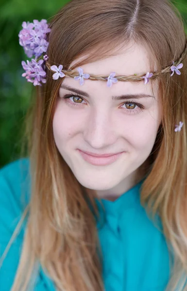 Hermosa mujer con una corona de lila en el jardín de primavera — Foto de Stock