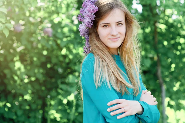 Schöne Frau mit fliederfarbenem Kranz im Frühlingsgarten — Stockfoto