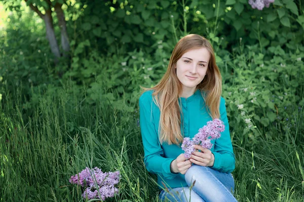 Belle femme avec une branche de lilas dans le jardin du printemps — Photo