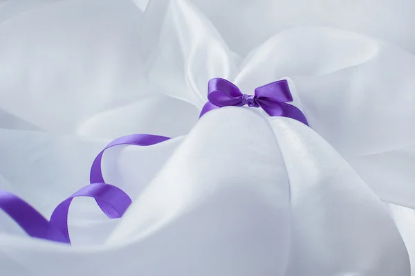Purple ribbon with bow on a white cloth — Stock Photo, Image