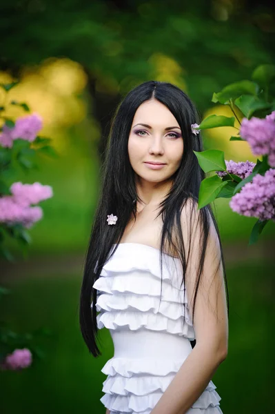 Krásná žena v zahradě kvetoucí šeříky — Stock fotografie