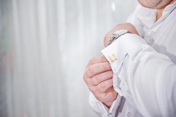 Man puts cufflinks on sleeve white shirts — Stock Photo, Image