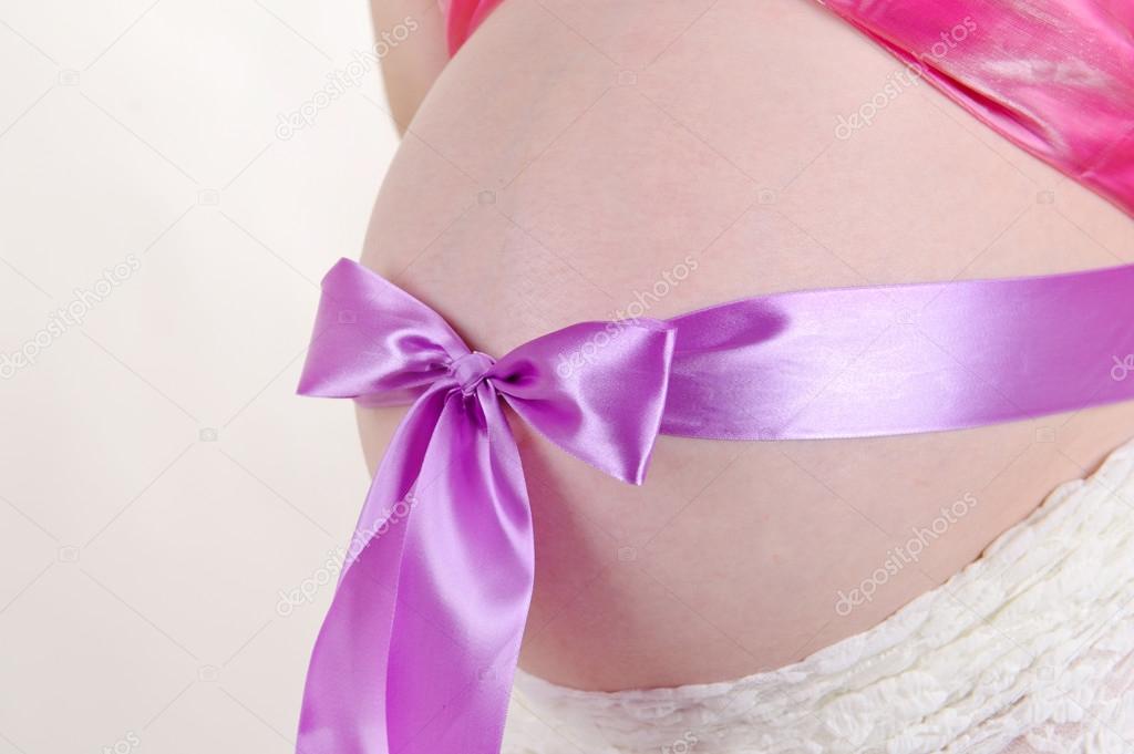 belly of pregnant woman tied with purple bow