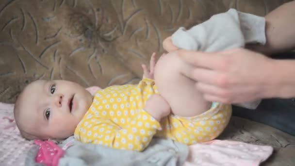 Молодой счастливый отец одевает свою дочь на диван в спальне — стоковое видео