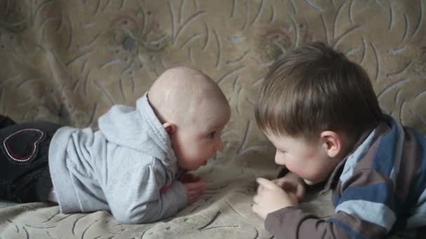 Kis testvérpár feküdt a kanapén, egymással szemben — Stock videók