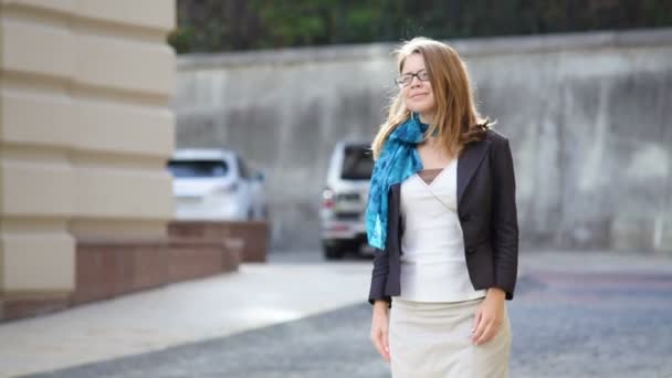 Glückliche junge trendige Frau mit Brille, die in einer urbanen Stadt spaziert — Stockvideo