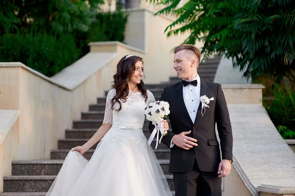 Bruden och brudgummen går uppför trappan i park — Stockfoto