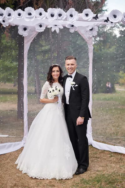 Bruden och brudgummen stå nära arch på bröllop — Stockfoto