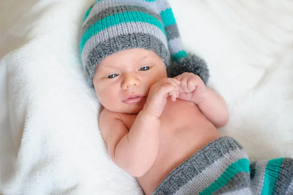 Piccolo bambino in maglia cappello sdraiato sul letto — Foto Stock