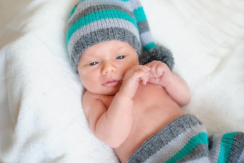 little baby boy in knitted hat lying on the bed