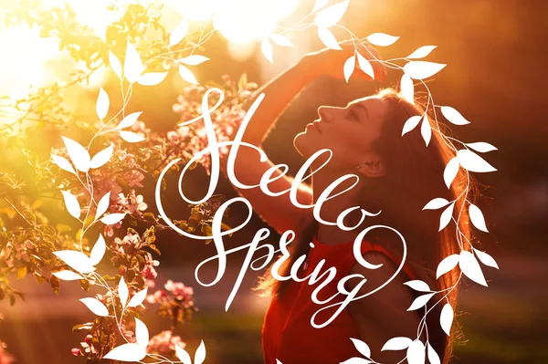Young woman enjoying smell in a flowering spring garden with letters Hello sprint — Stock Photo, Image