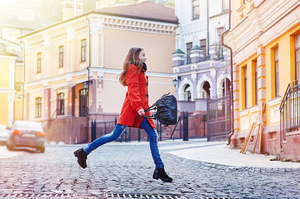Bela jovem com saco em casaco laranja andando na rua — Fotografia de Stock