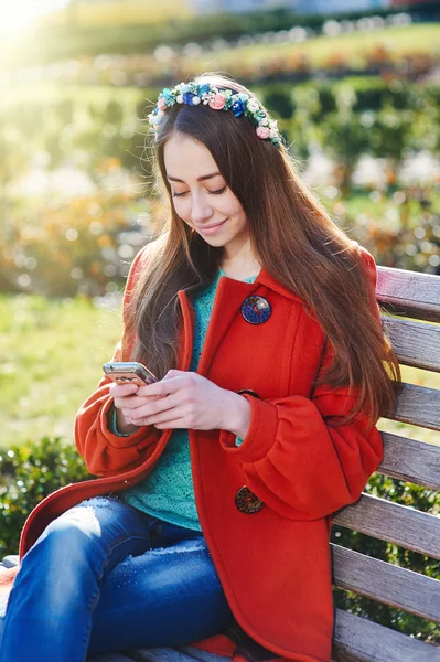 Vacker kvinna kappa sitter på bänken i staden — Stockfoto