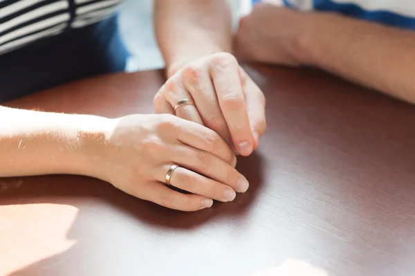 Close up arms of loving couple sitting at the table in cafe — Stock Photo, Image