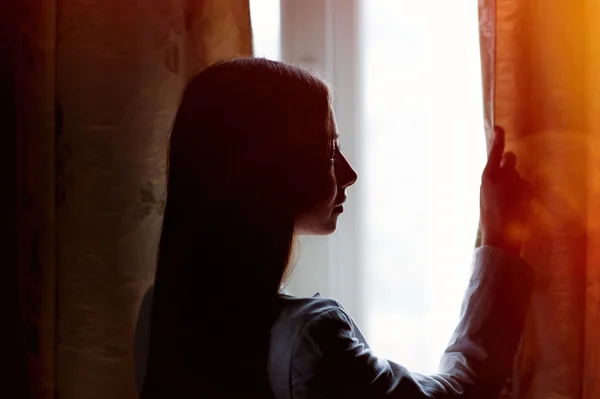 Όμορφη νεαρή γυναίκα που στέκεται κοντά σε ένα παράθυρο στο δωμάτιο — Φωτογραφία Αρχείου