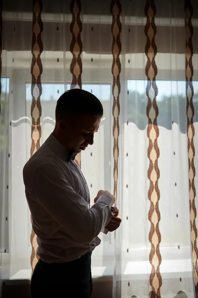 Groom silhouette dress cufflinks near the window — Stock Photo, Image