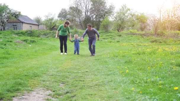 Mutlu genç aile dışarıda yeşil doğada birlikte vakit geçiriyor. — Stok video