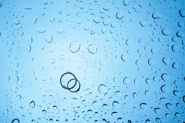 Fond gouttes d'eau et deux anneaux sur le verre — Photo