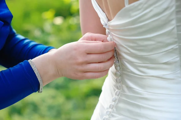 Подружка невесты помогает невесте одеться в день свадьбы — стоковое фото