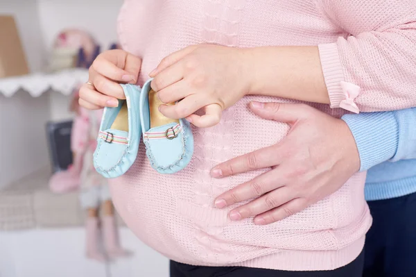 Pregnant woman hugging her husband and they keep booties for unborn child — Stock Photo, Image