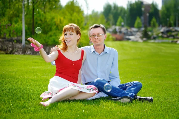 Couple love sitting on green grass in summer meadow Stock Picture