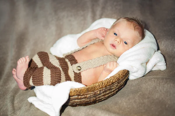Mały chłopiec w pasiastej spodnie leżąc na łóżku — Zdjęcie stockowe