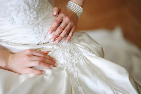 Elegant hands of bride against background dress — Stock Photo, Image