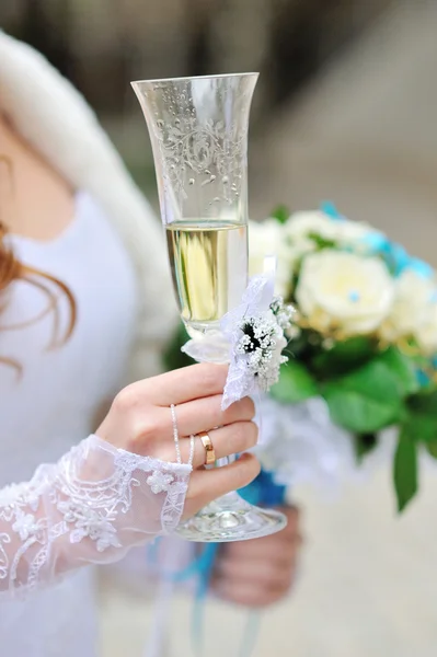 Bride is holding wedding bouquet and glass of champagne — Stock Photo, Image