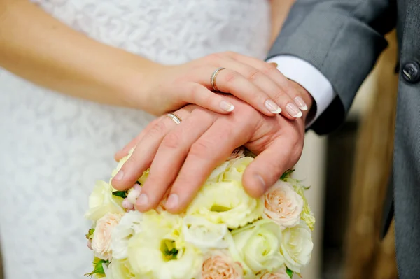 Hands of bride and groom on the bouquet roses — Stock Photo, Image