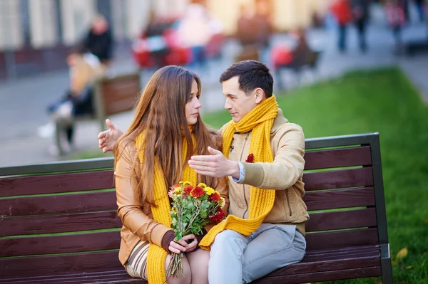 Linda pareja joven sentada en el banco del parque y hablando durante la cita — Foto de Stock